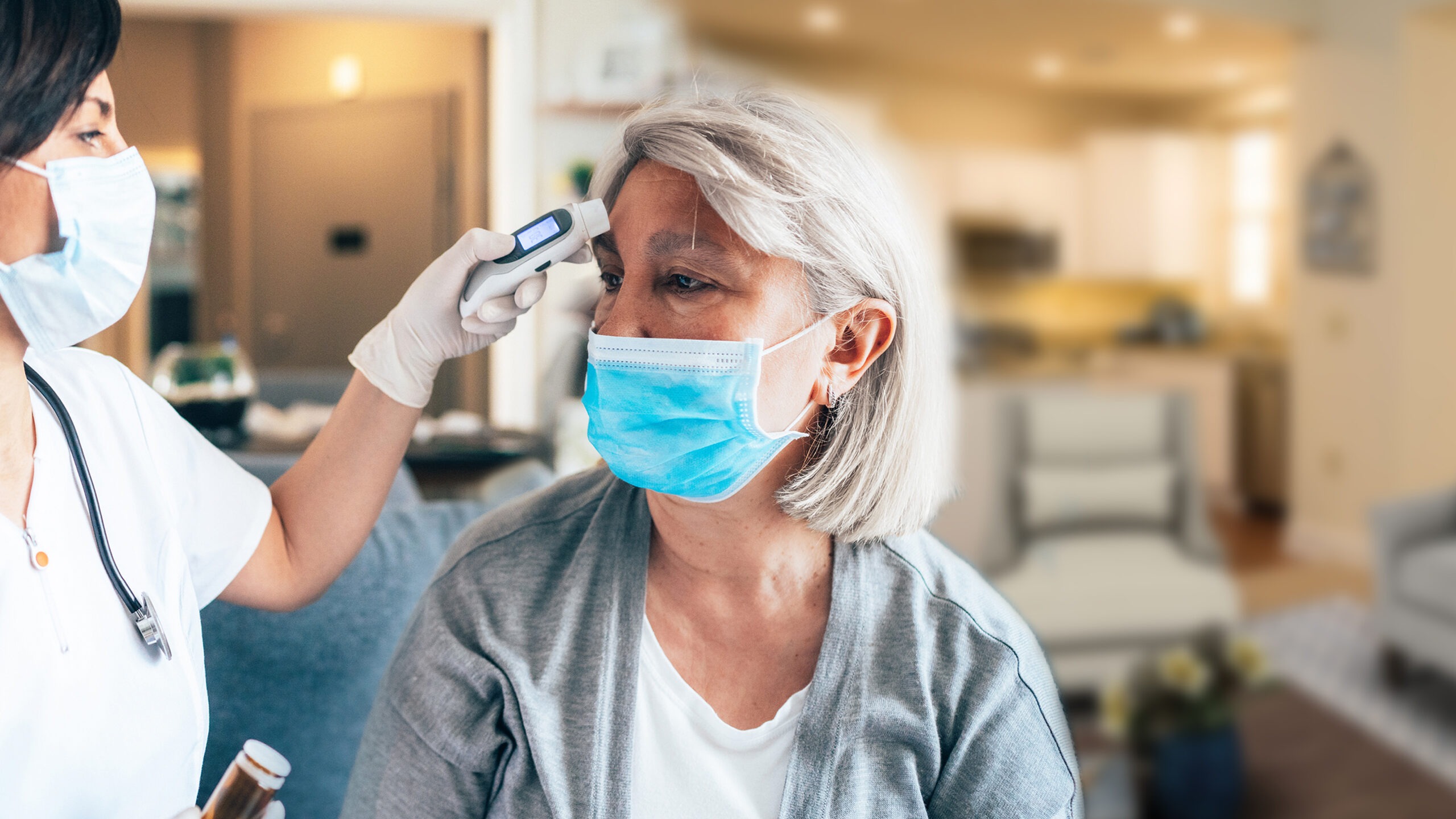 Nurse taking residents temperature wearing masks