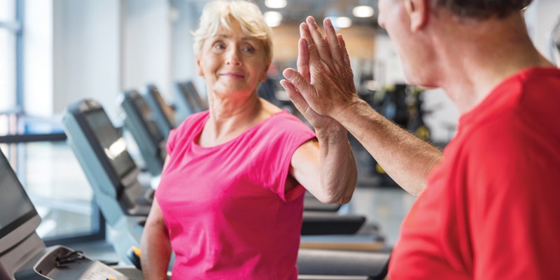 two residents walking on a treadmill highfiving